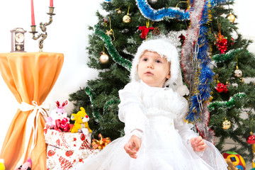 A small child - a girl on a swing near the Christmas tree