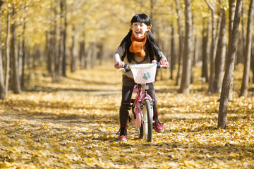 Little girl cycling in autumn woods