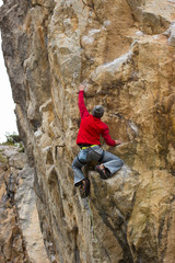 Young male climber hanging on a cliff with a rope.