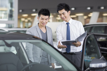 Young man choosing car in showroom