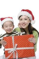 Mother and son with Santa hats holding gift box