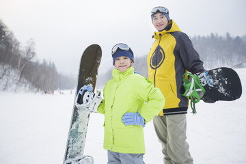 Young father and son with snowboards on the snow