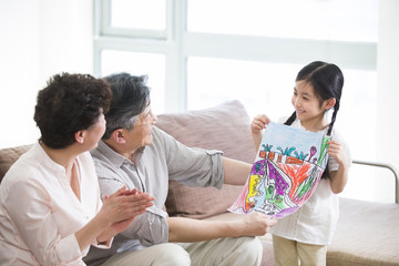 Cute girl showing drawing to grandparents