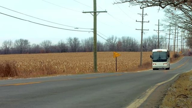 Coach (bus) passing a field of corn (maize).  Wide view, colored for a fall/autumn look.  Originally recorded in 4K, UHD.