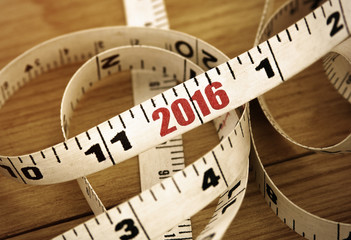 Tape line with red numbers 2016 on wooden background. New Year 2016 concept. Toned image.