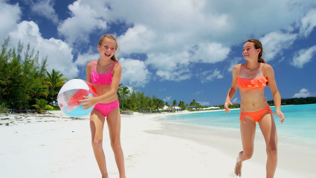 Happy young female Caucasian children in swimwear playing with a beach ball