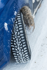 Close up of a cars tires on a snowy road.