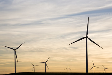 Fototapeta premium Silhouettes of wind turbines on sunset sky background