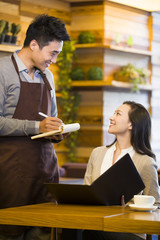 Waiter taking order from woman at restaurant