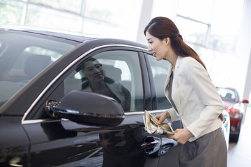 Fototapeta na wymiar Young businesswoman choosing car in showroom