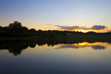 Naklejka na ściany i meble Sun rising over a small lake