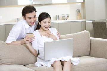 Obraz na płótnie Canvas Young couple using a laptop at home