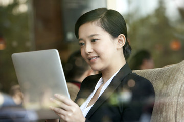 Cheerful businesswoman playing digital tablet in cafe