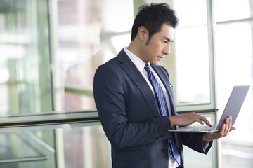 Young businessman using laptop in airport