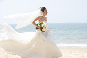 Happy bride running on the beach