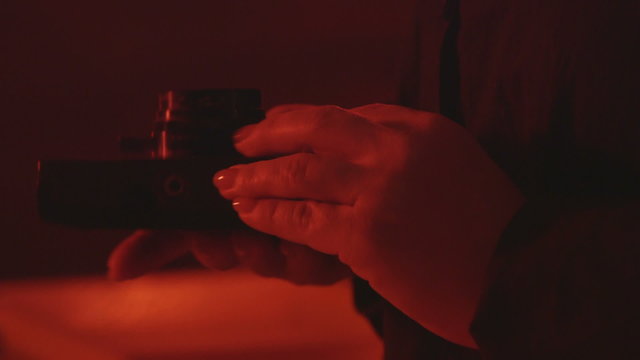 Female photographer holding Soviet vintage camera Smena Symbol manufactured at the enterprise LOMO in red darkroom