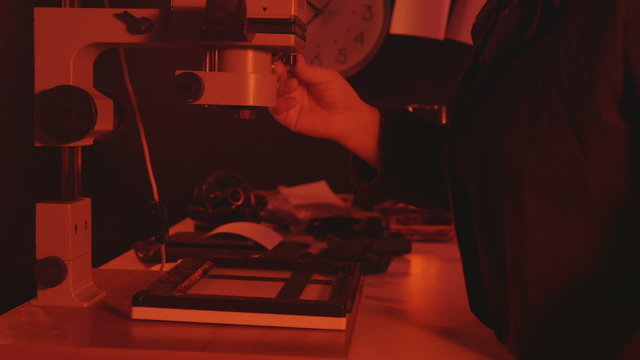 Exposure of the image onto sensitized paper using photographic enlarger in darkroom