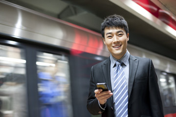 Chinese businessman using cellphone in the subway station
