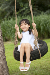 Excited little girl playing on a swing 