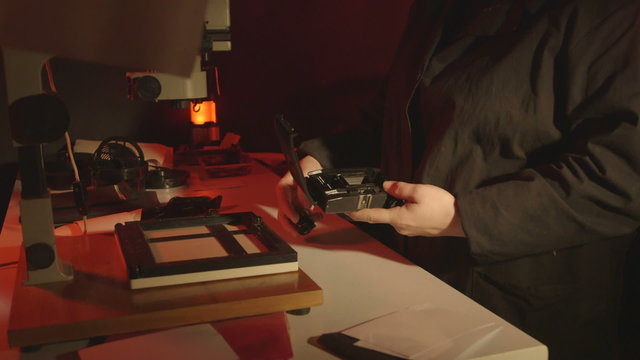 Woman photographer loads new film into her 35mm Lomo Smena Symbol camera in photography darkroom