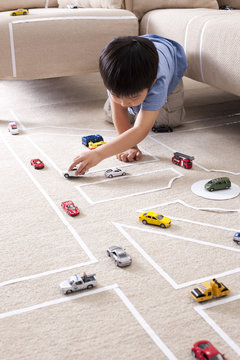 Boy playing with his car toys at home
