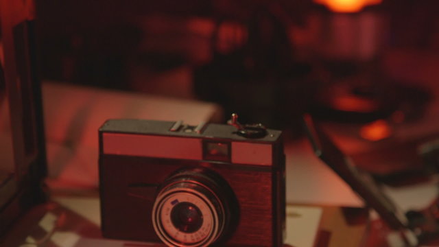 Vintage 35mm camera Lomo Smena Symbol and enlarger in red photography darkroom close-up dolly shot
