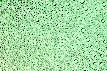 Water drops on transparent green glass surface.