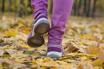 to walk on leaves in sneakers. convenient sports shoes on a foot. stylish fashionable footwear