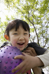Young Girl Holding A Ball In The Park And Smiling