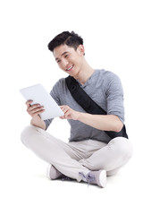 Happy male college student with digital tablet sitting cross-legged