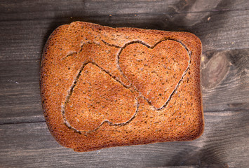 Two hearts which are cut out in a piece of rye bread