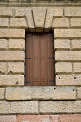 Okno z drewnianymi okiennicami w kamiennej ścianie zabytkowego budynku w Weronie - Włochy