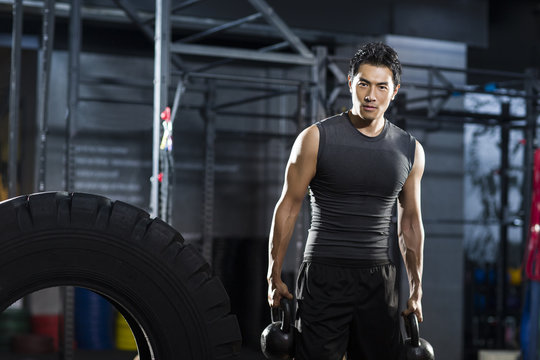 Young man training with kettlebells in crossfit gym