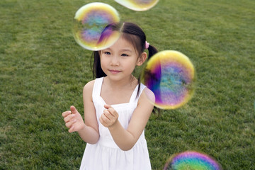 Young Girl Chasing Bubbles In Park