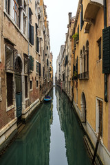Fototapeta na wymiar Picturesque view of Gondolas on lateral narrow Canal on a foggy day, Venice, Italy.