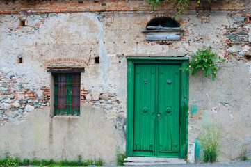 Old italian stone house front with green door