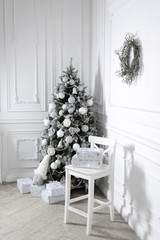 Beautiful holdiay decorated room with Christmas tree with presents under it. Christmas tree decorated by artificial flowers and bow