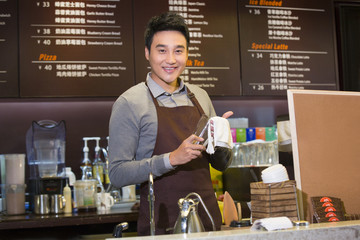Male coffee store clerk rubbing glass cups