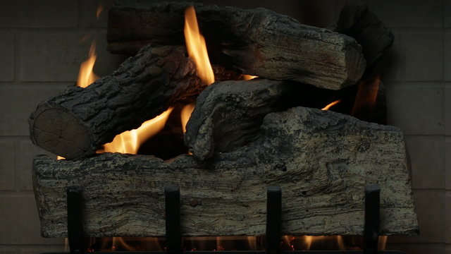 Logs burning in a gas fireplace (dolly shot).