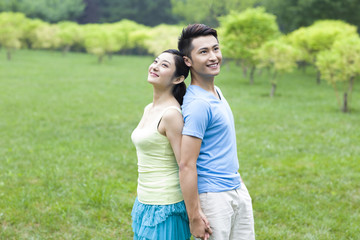 Obraz premium Sweet young couple in park, back to back