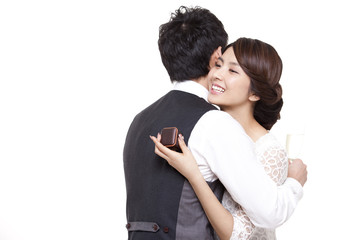 Happy young woman embracing young man with a ring in hand