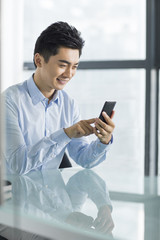 Young businessman using smart phone in office