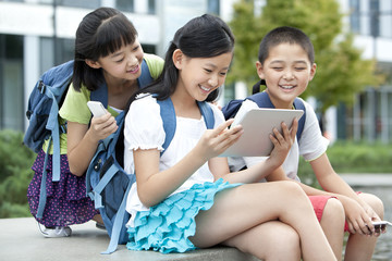 Schoolchildren playing digital tablet together