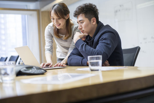 Business people using laptop in board room