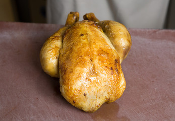Whole Roast chicken on a rustic textured cutting board