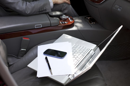 Laptop and mobile phone on car seat