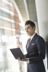 Young businessman using laptop in airport