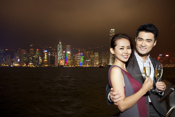 Happy young couple enjoying the night view of Victoria Harbor with champagne, Hong Kong