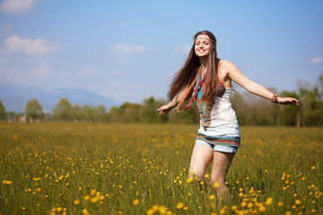 Naklejka na ściany i meble Smiling hippie in summer flowers field