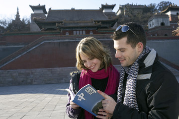 Young Couple Visiting The Forbidden City Looking At Guide Book 